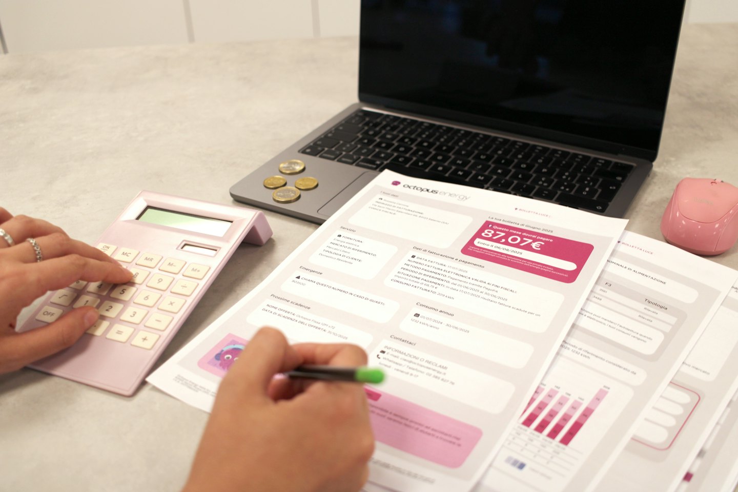 Person prüft eine Stromrechnung mit Taschenrechner und Stift vor einem Laptop